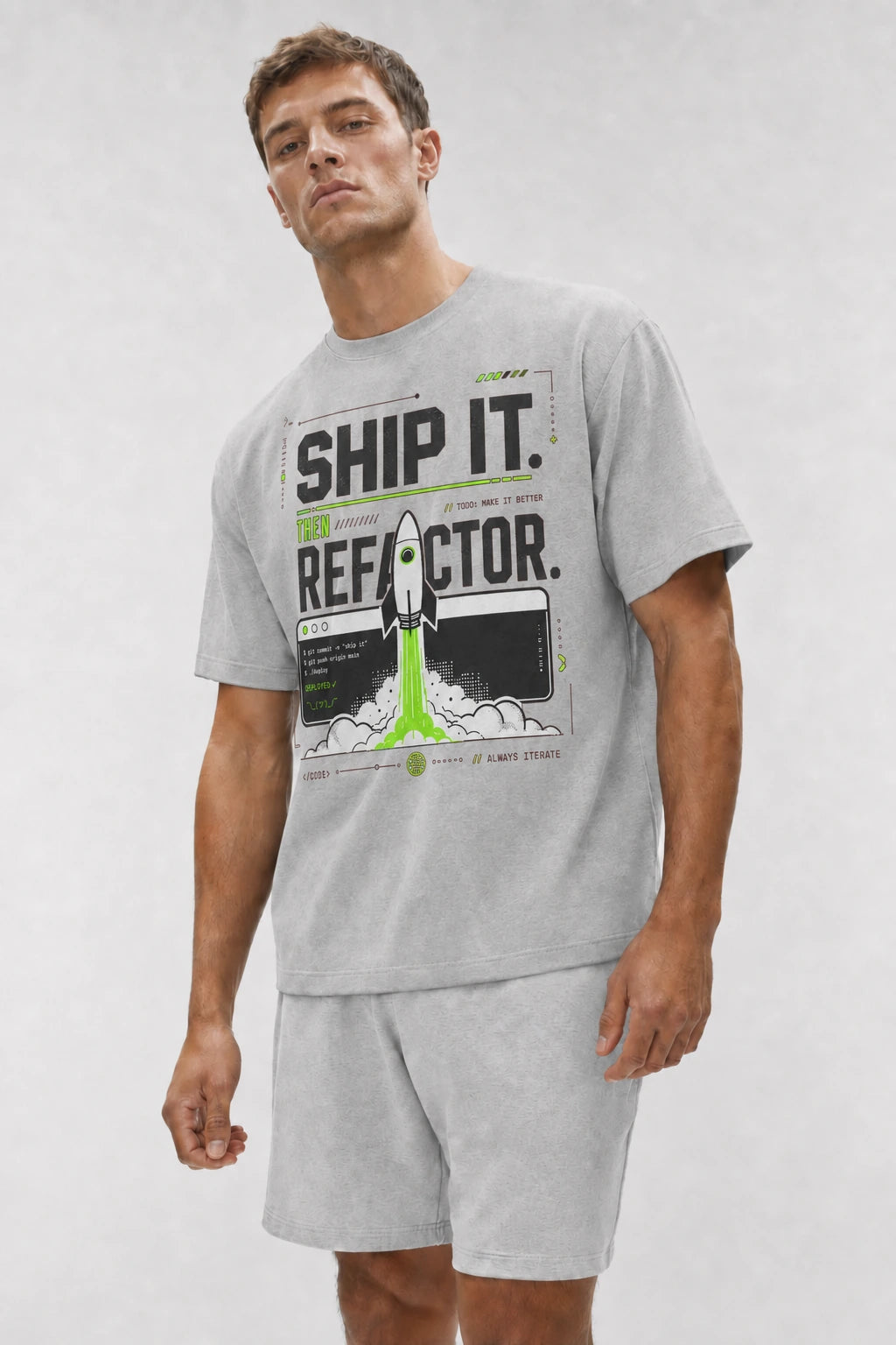 Close-up of a model wearing the Athletic Heather Ship It. Then Refactor. tee with a neon green rocket and terminal graphic.