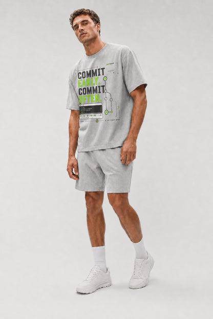 Uncropped full-body view of a model wearing the Athletic Heather Commit Early. Commit Often. oversized boxy tee.